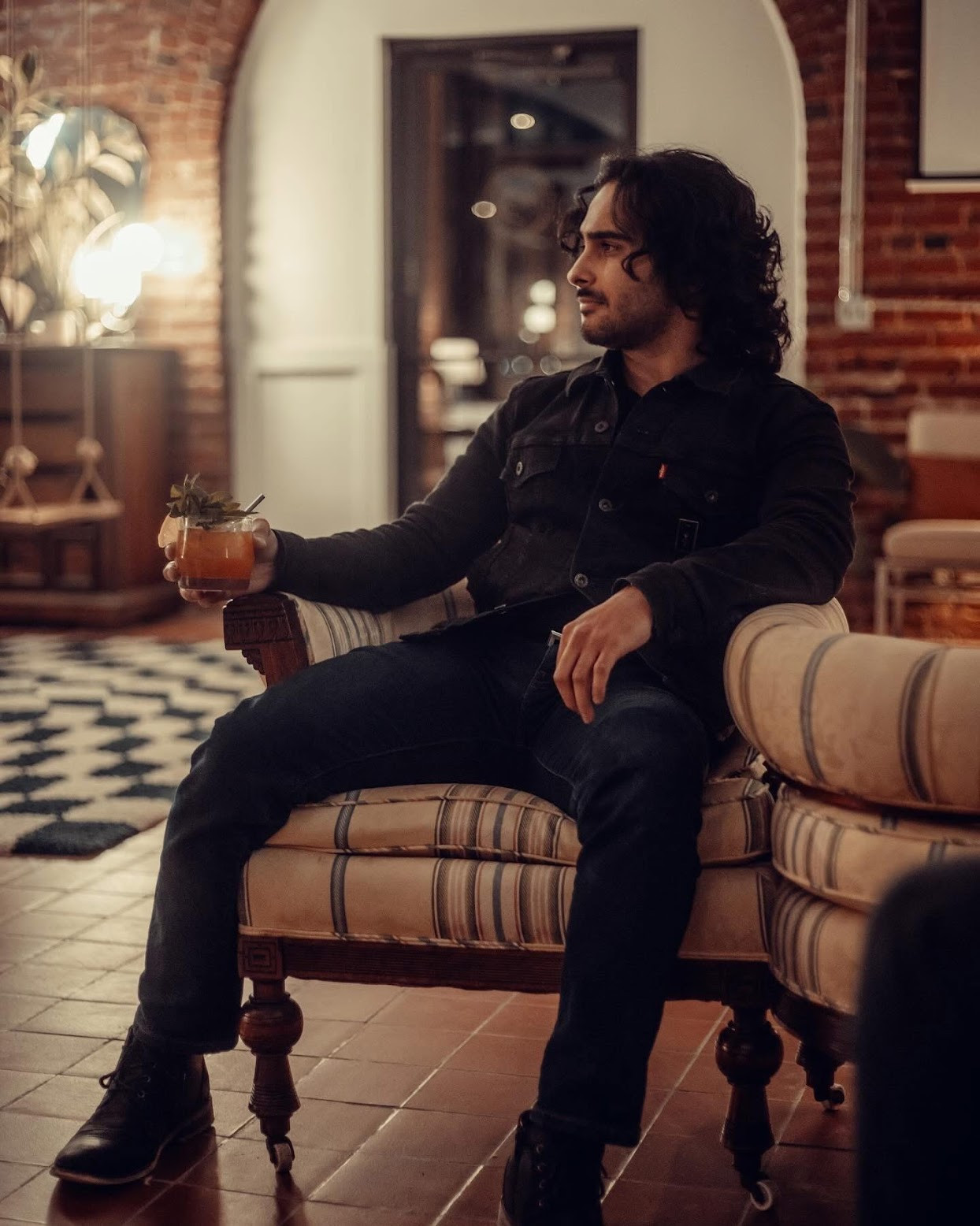 Alex relaxing in an armchair with a cocktail